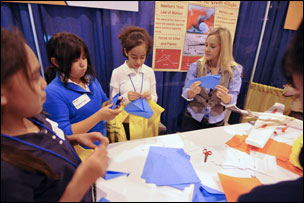 Students learn about the aerodynamics of paper airplanes at a UC Denver booth during STEMapalooza at the Colorado Convention Center on Friday, Oct. 16.